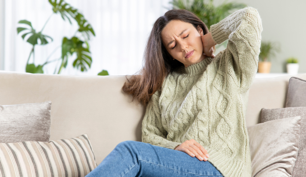Woman on couch holding her neck in pain