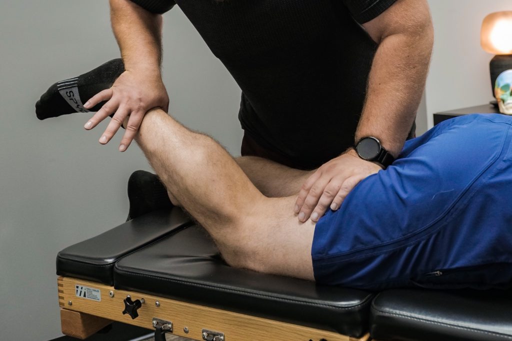 Dr. Bryan Pankow performing applied kinesiology muscle testing on an athlete’s hamstring at Nobility Chiropractic in Smiths Falls